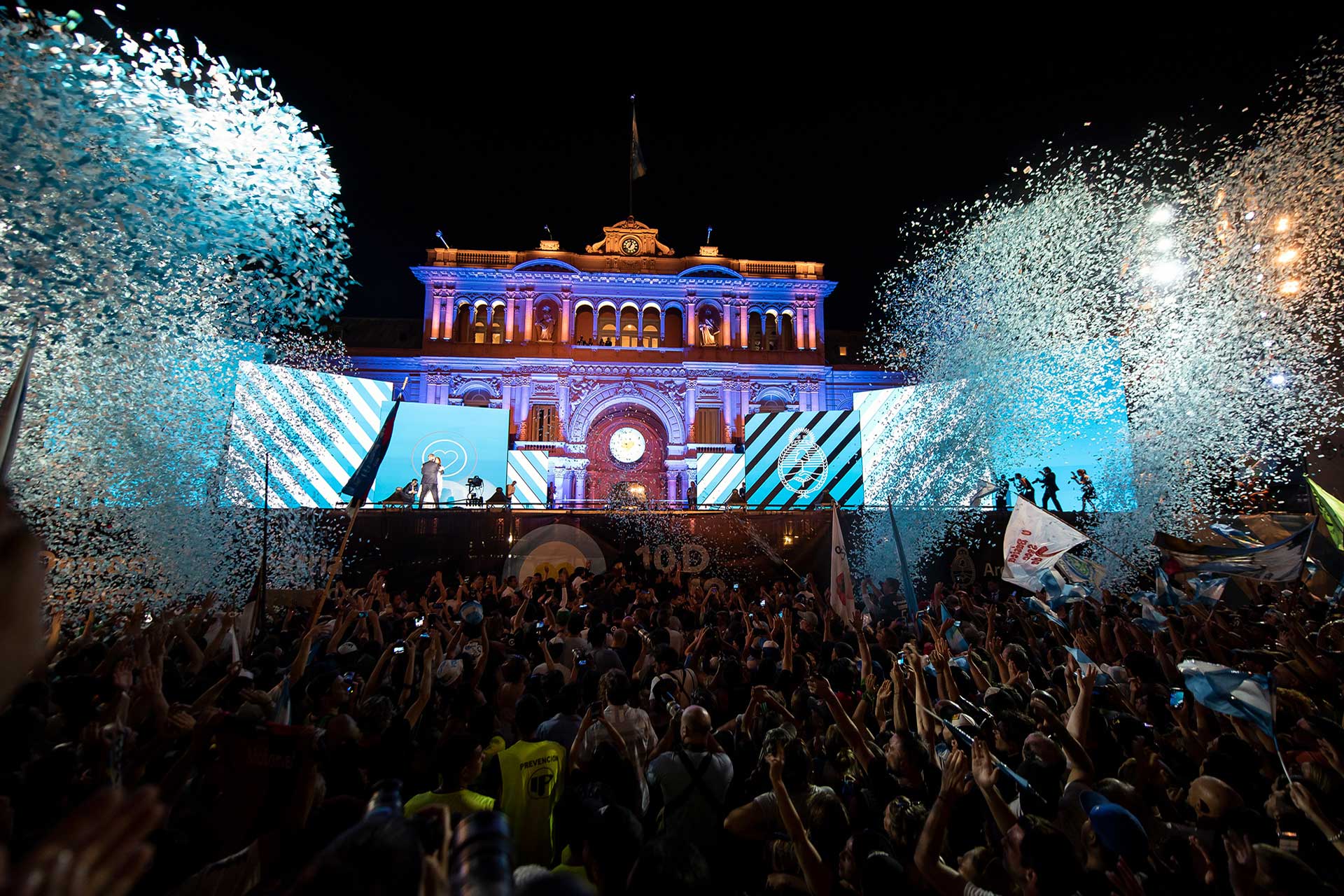 Fotografía de Alberto Fernández y Cristina Fernández de Kirchner ingresando al escenario montado frente a 'Casa Rosada'. En la plaza, una multitud festejando