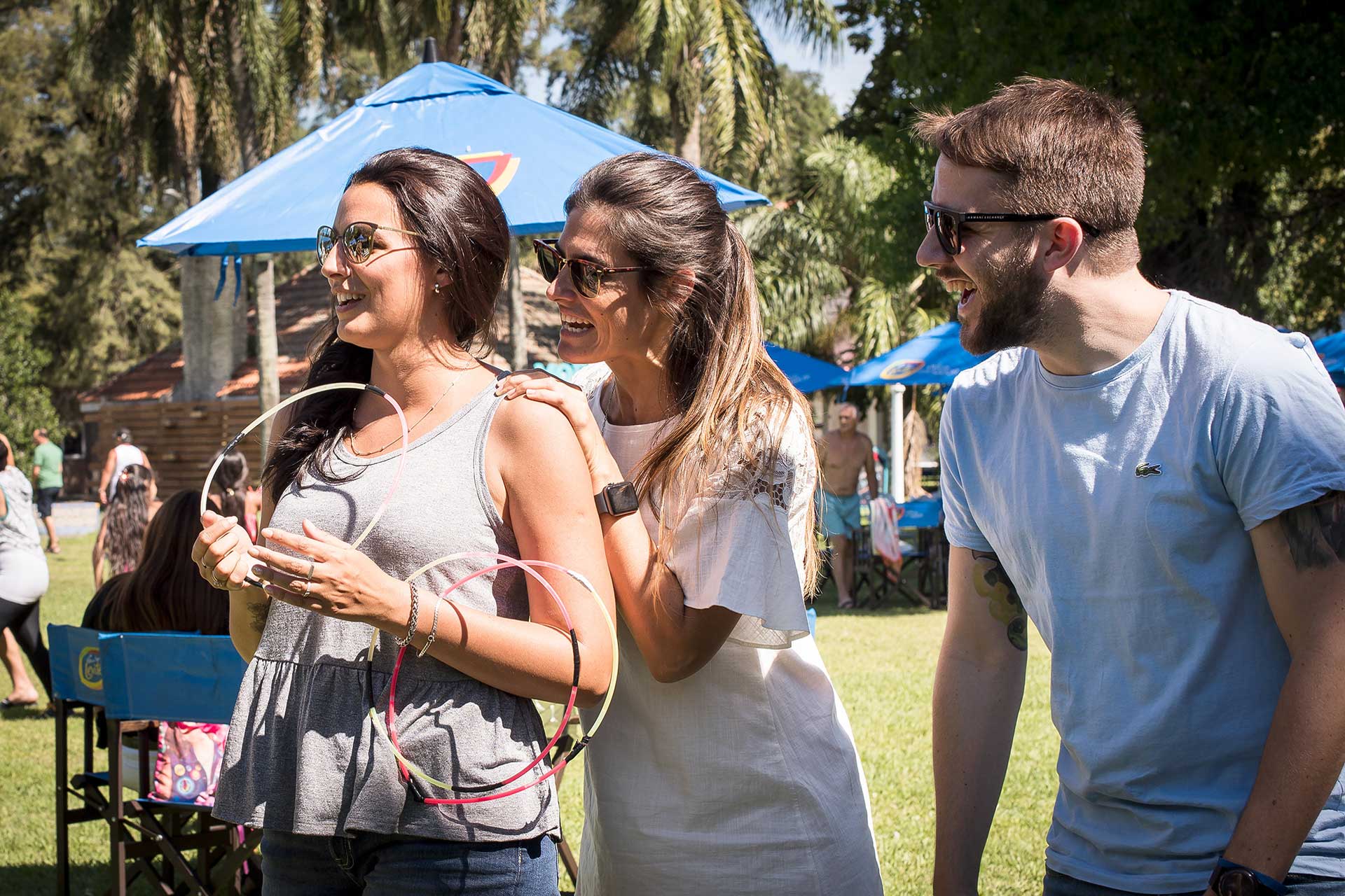 Fotografía de dos mujeres y un hombre jugando a arrojar aros durante el evento, matutino, organizado por la empresa 'Danone Argentina'