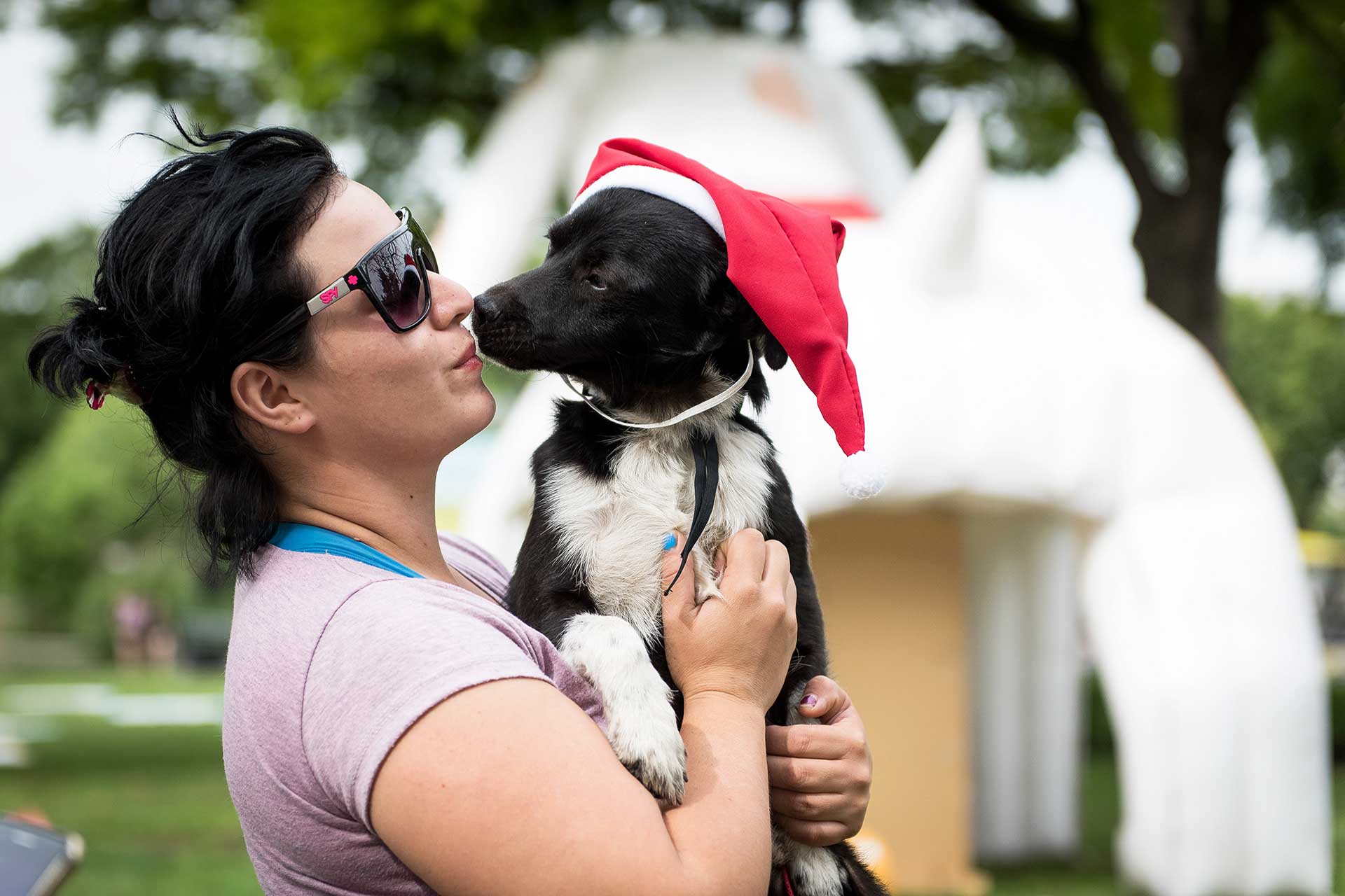 Fotografía de mujer con su perro en brazos a punto de besarse, el perro lleva un gorro navideño. Cobertura del evento 'Mascotas de la Ciudad', organizado por el Gobierno de la Ciudad Autónoma de Buenos Aires