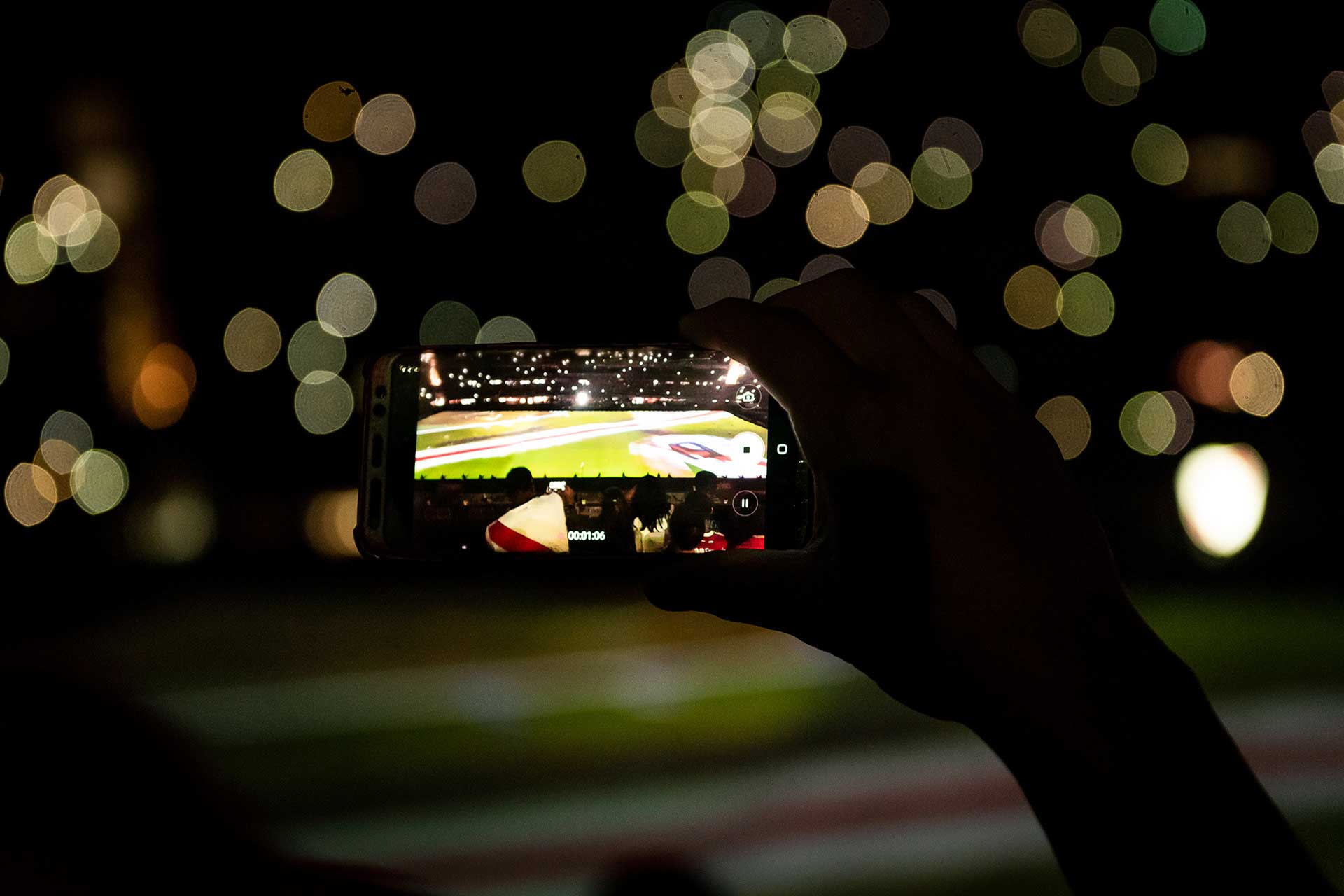 Fotografía en primer plano de la pantalla de celular de un hincha captando el momento desde la tribuna. El celular es sostenido por la mano del hincha. Cobertura del evento '09-12 eterno' organizado por el Club Atlético River Plate