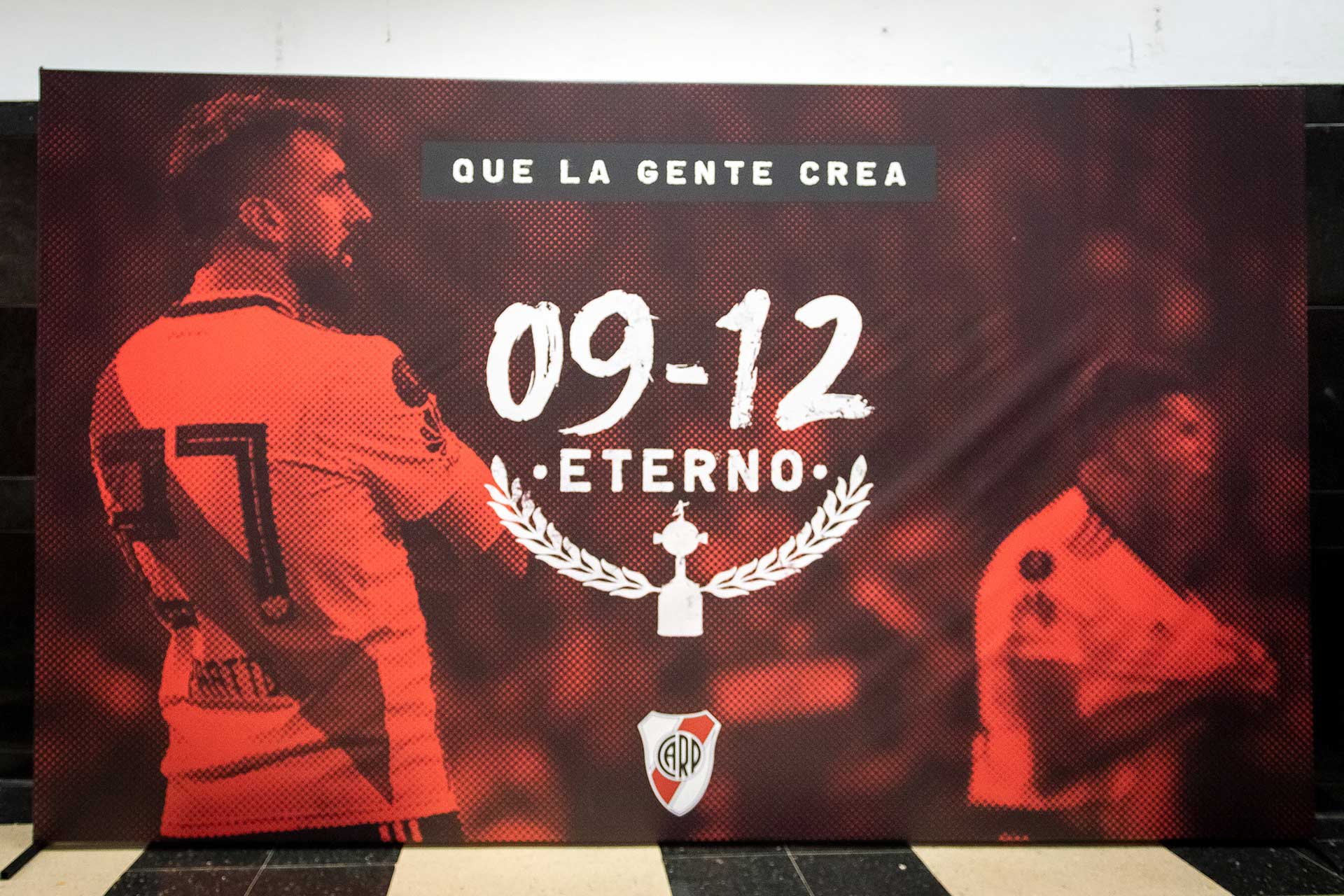 Fotografía de afiche 'Que la gente crea 09-12 eterno' proyectado en la pantalla del estadio de River Plate para el mencionado evento