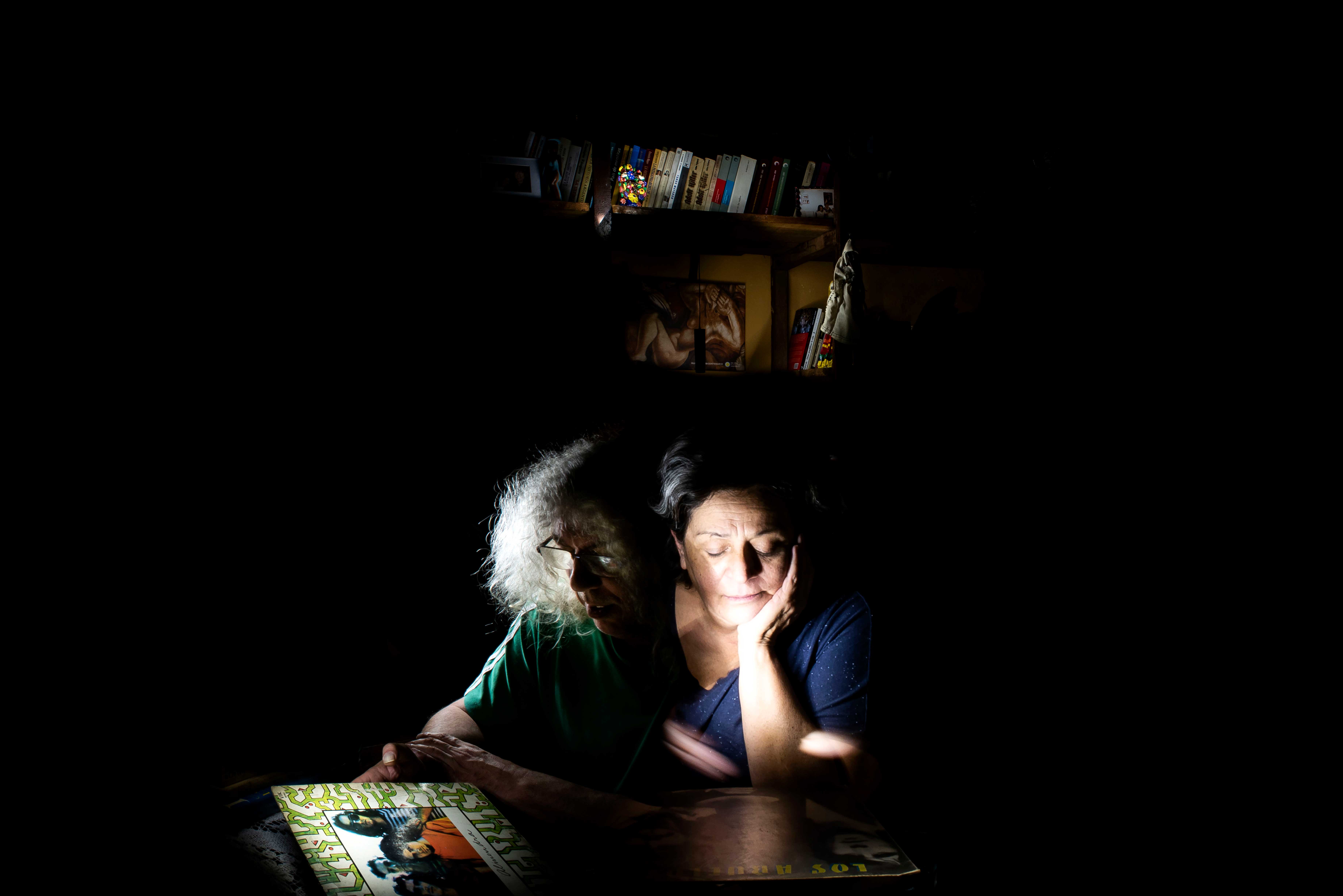 fotografia de los padres de la artista, mirando tapas de discos de vinilo en plena obscuridad