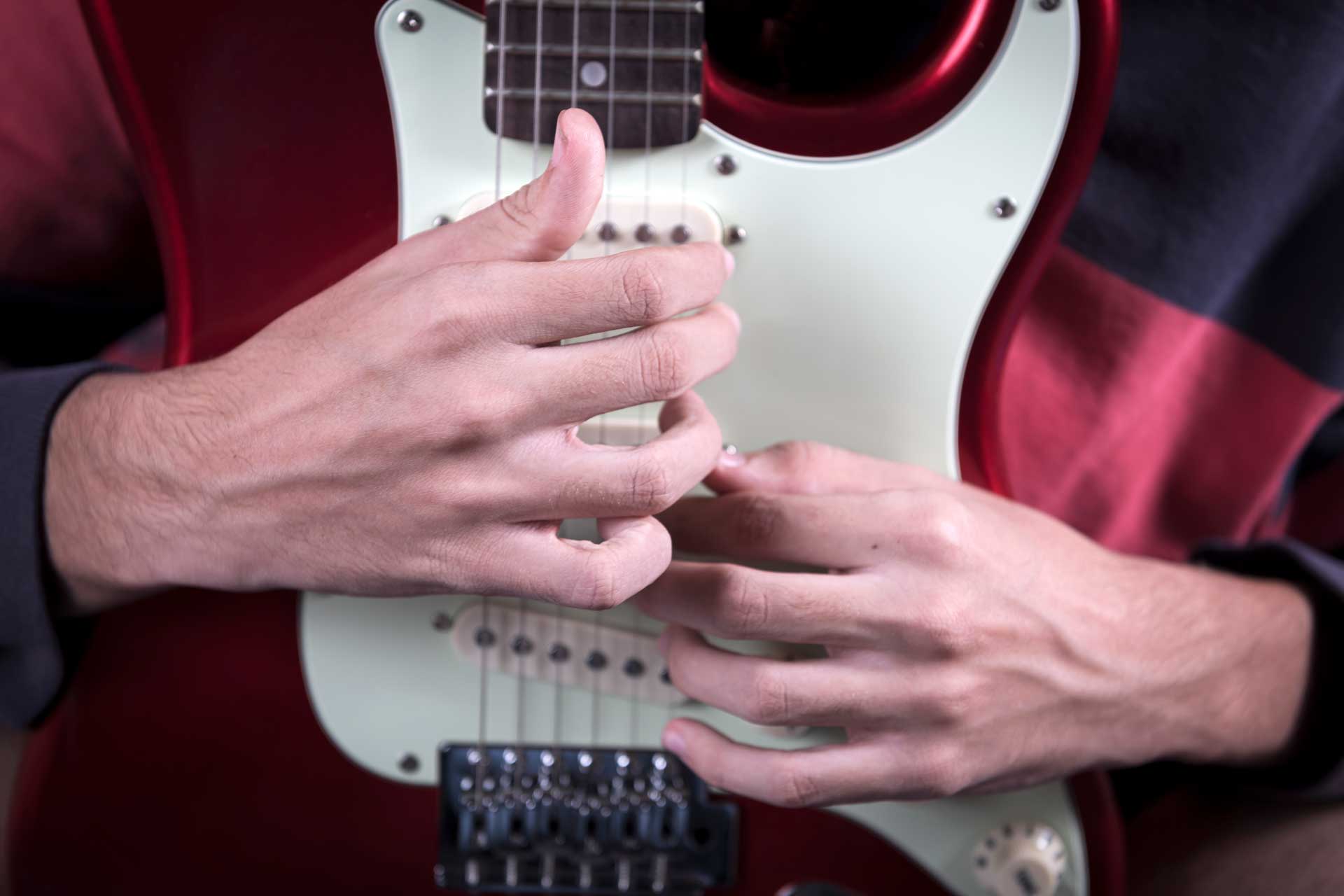 fotografia, en primer plano, del cuerpo de la guitarra con las dos manos de su hijo sobre ella