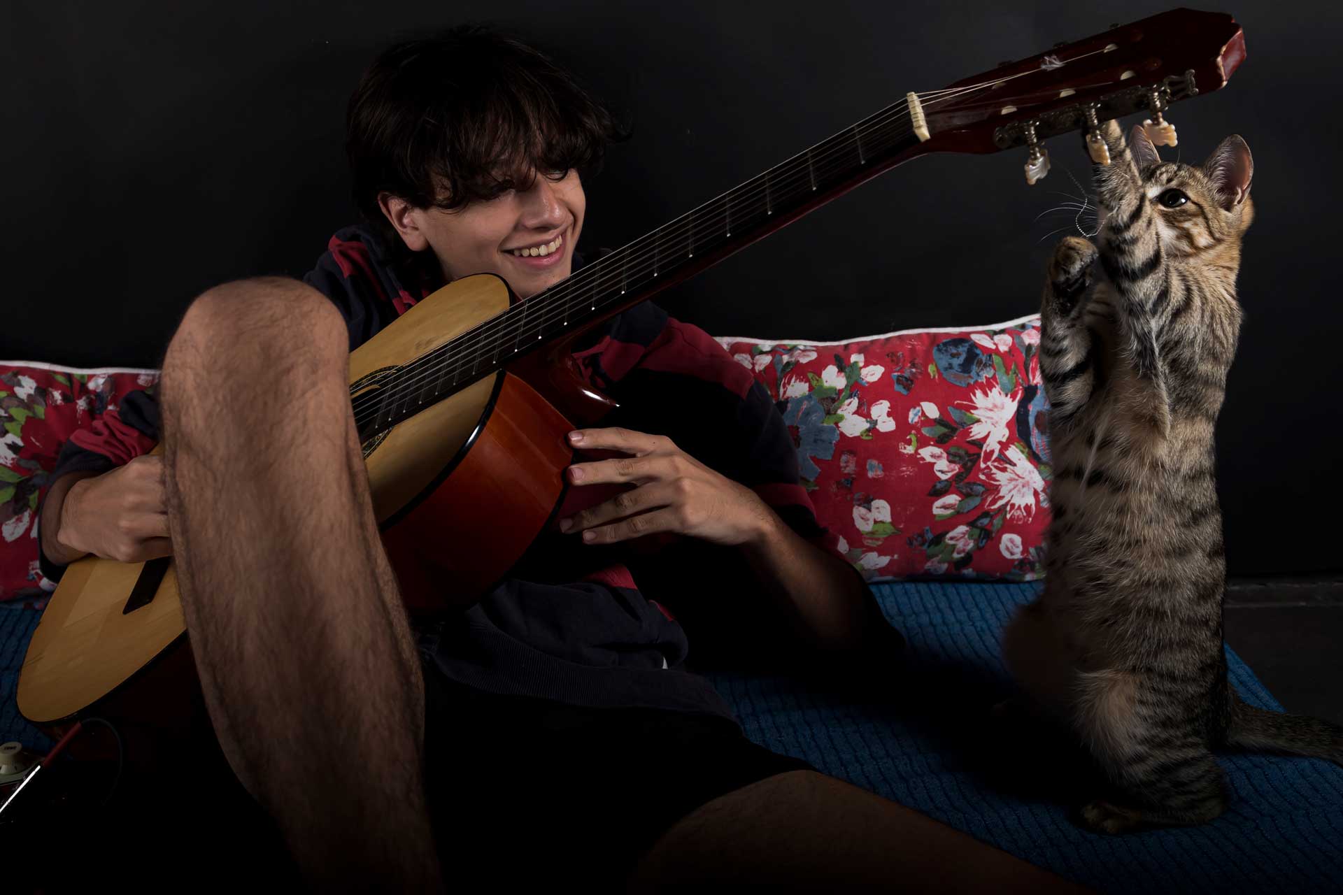 fotografia del hijo de la artista recostado sobre una antigua cuna, observando como su gato juega con las cuerdas del traste