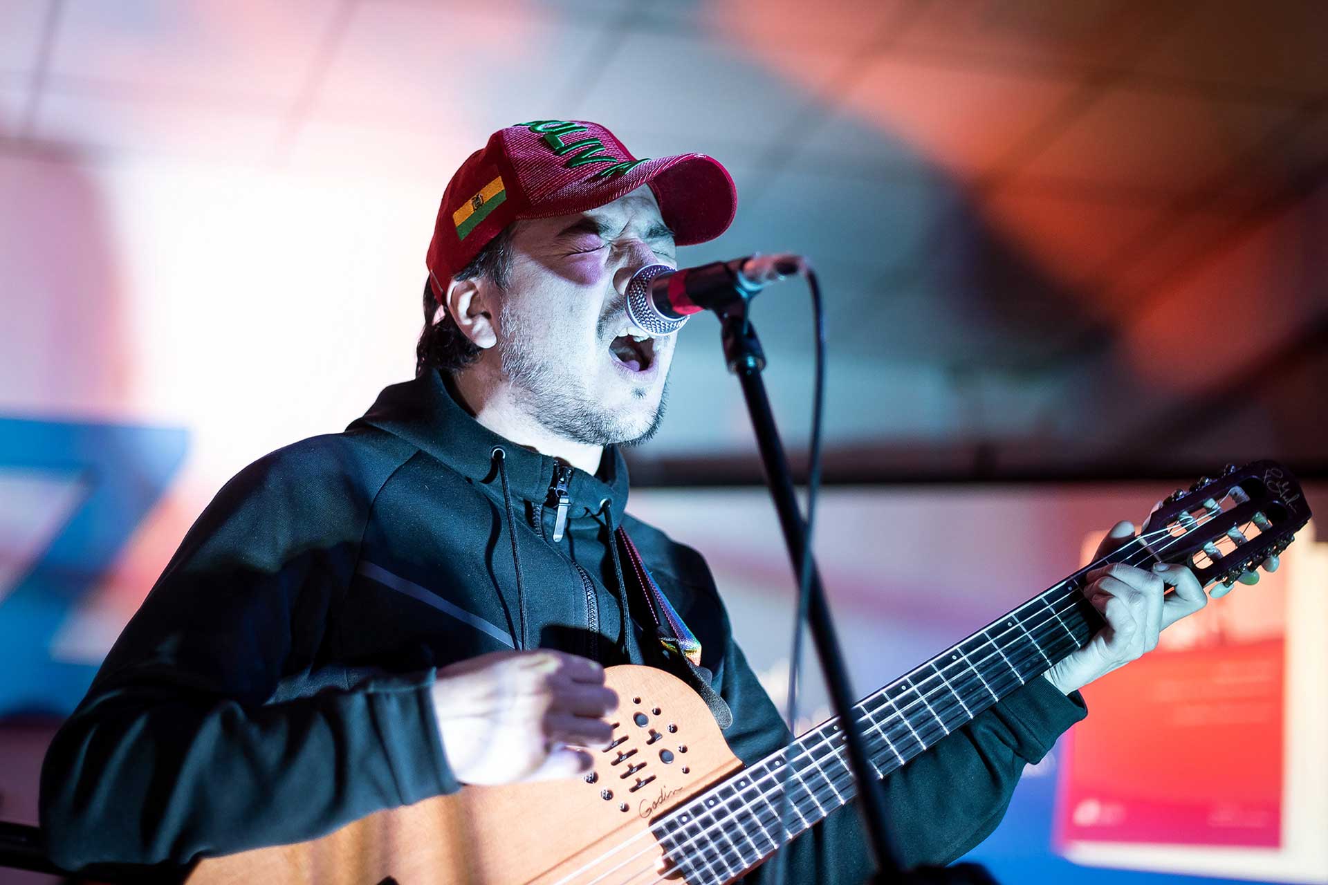 Fotografía, en primer plano, de Bruno Arias cantando mientras toca su guitarra